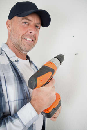 happy man drills a wall with a drillの写真素材
