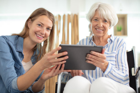 aged woman and her adult daughter using tabletの写真素材