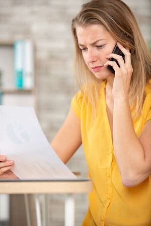 young businesswoman talking by phone with paperの写真素材