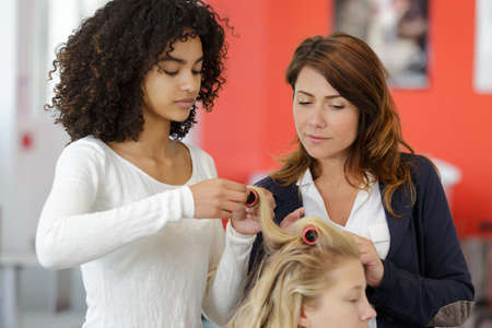 hairdresser teaching her work to a young aspirantの写真素材