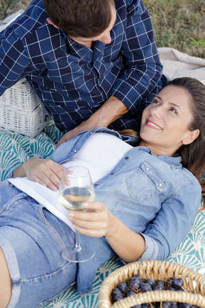 couple sitting on a picnic blanket with wine glasses outsideの写真素材
