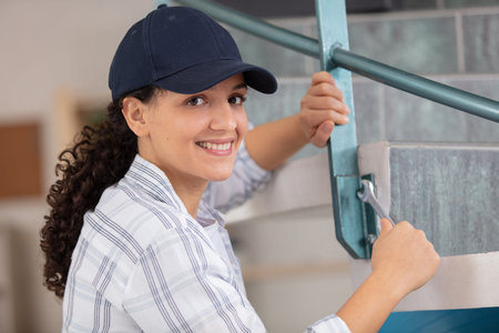 female contractor repairs metal staircase with a spanner