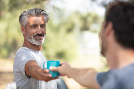 man brings coffee to friend drink to go outdoorsの写真素材