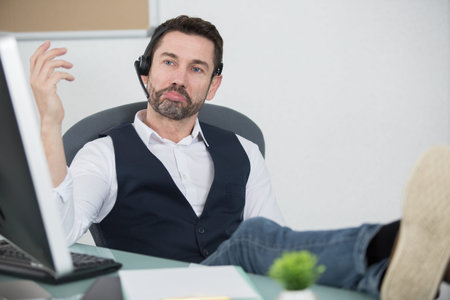 cool cheerful smiling director put legs in shoes on table