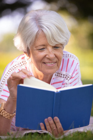 retired woman reading a book on the park