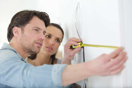 couple measuring a wall with tape meterの写真素材