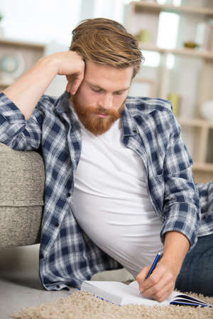 hipster taking notes on notebooks on the floorの写真素材