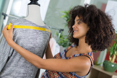 female dressmaker taking measurement on mannequin