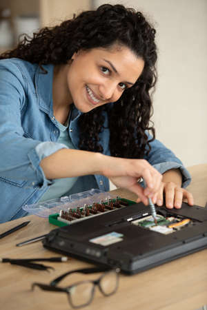 happy young woman repairing computerの写真素材