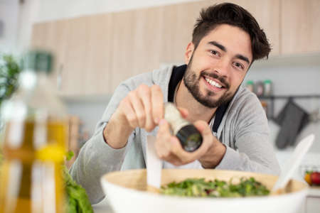 closeup of happy smiling man preparing green saladの写真素材