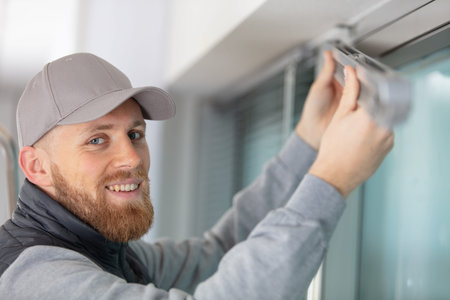 man installing window blinds in a house