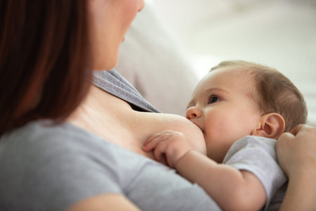 mother breastfeeding and hugging baby