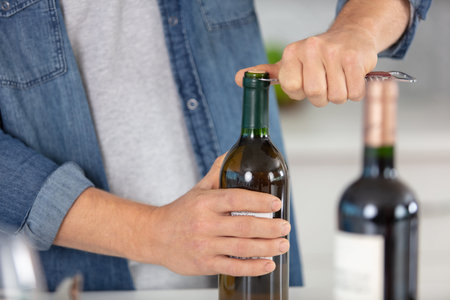 cropped view of man opening a bottle of wineの写真素材