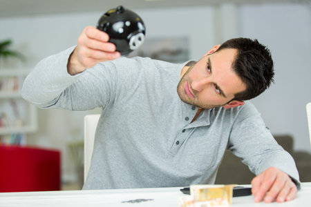 young businessman is looking in empty piggy money bankの写真素材