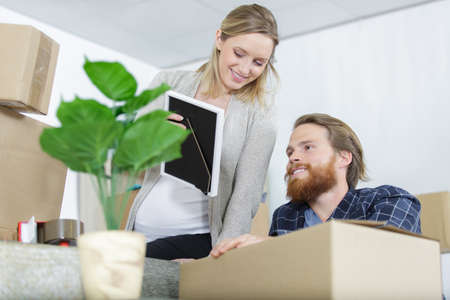 young couple looking at a picture frame while unpackingの写真素材