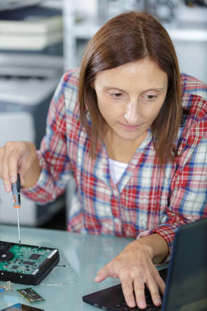 female unscrewing a back of a laptopの写真素材