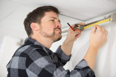 man installing window curtain rod on the wall