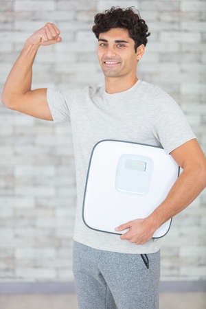 a weight loss male holding weighing scaleの写真素材