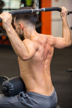 young man using cable machine in gym