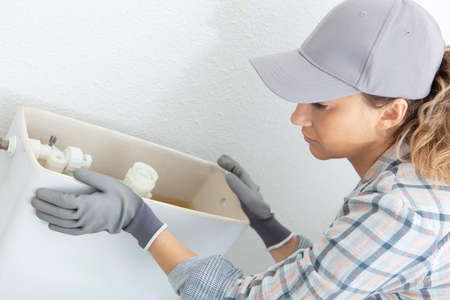 female plumber installing a toilet cisternの写真素材