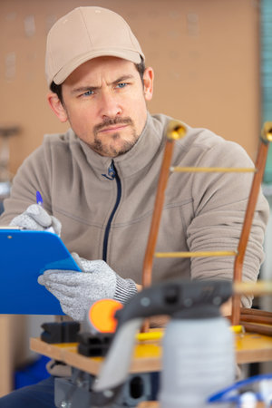 man builder writing on clipboard inspecting construction site