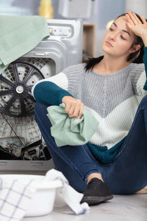 young lady trying to repair a washing machineの写真素材