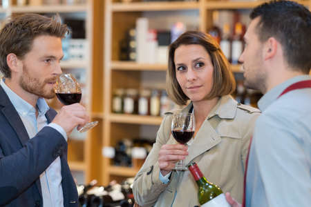 couple during a wine tasting with sommelier assisting themの写真素材