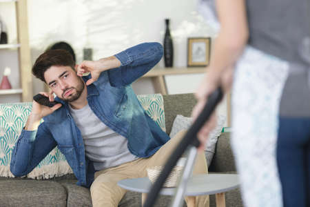 man covering ears while woman is hooveringの写真素材
