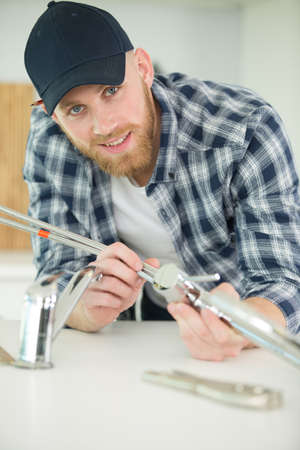 man fixing sink pipe in kitchenの写真素材
