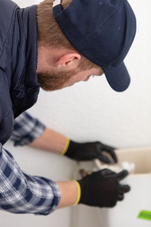 professional plumber working with toilet cistern in bathroom
