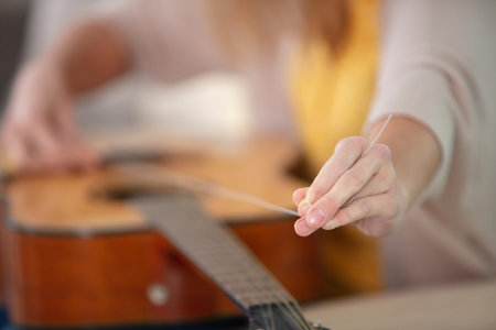 cropped image of woman changing guitar strings