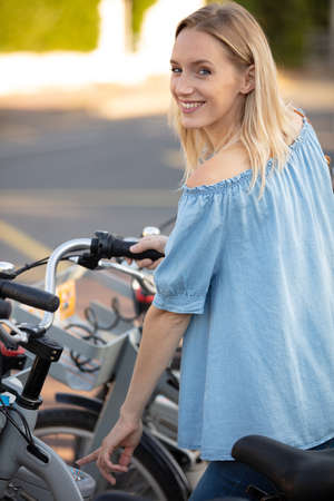 attractive girl unlocking rental bicycleの写真素材