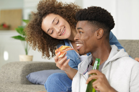 happy young couple with slice of pizza and beer