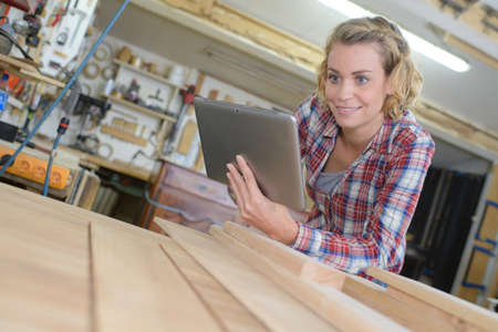 woman using tab and looking at wooden planksの写真素材