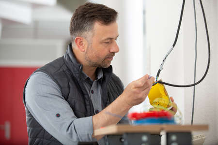 electrician working with hanging cords on the wallの写真素材
