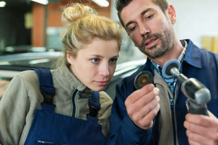 young female mechanic and teacher working on car engineの写真素材