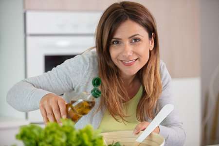 woman pouring olive oil into her bowl of lettuce