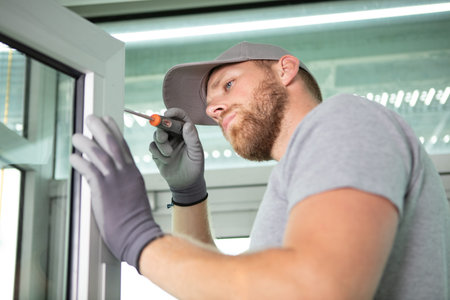 male contractor using screwdriver on pvc window