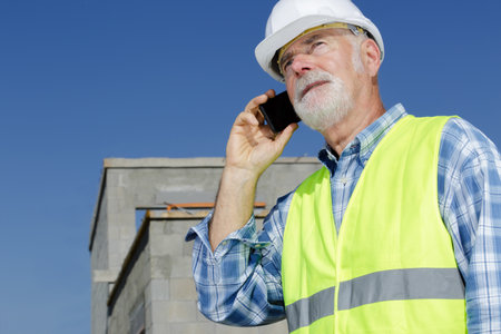 mature builder using telephone by a property under constructionの写真素材