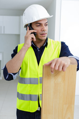 builder on phone holding plank