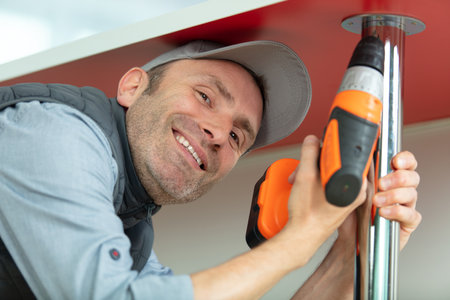 man with an electric screwdriver in his hand collects tableの写真素材