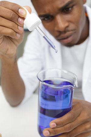young scientist with violet solution in pipette dropper
