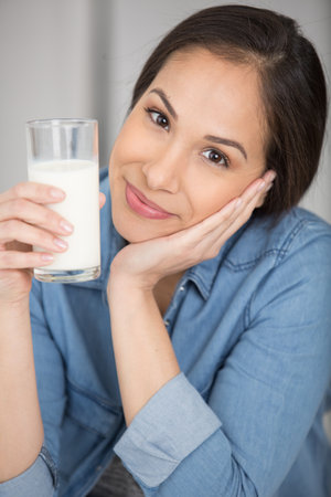 happy young woman drinking milkの写真素材