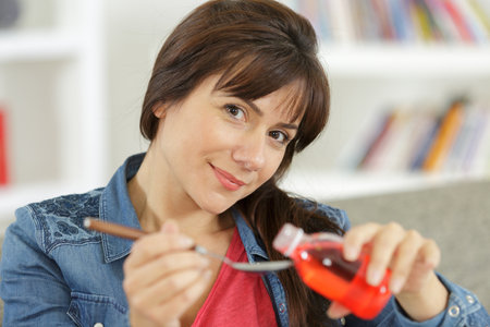 woman taking tincture syrup with spoonの写真素材