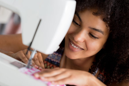 young female seamstress sewing fabric in a sewing machine