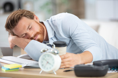 tired businessman sleeping on his deskの写真素材