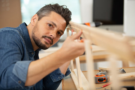 serious furniture designer carefully sanding a chairの写真素材