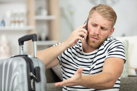 man using smartphone to report problem with suitcaseの写真素材