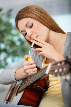 woman smoking a cigarette while playing guitarの写真素材
