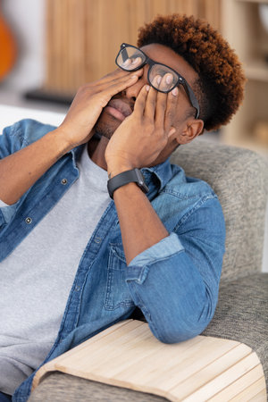 man suffering headache sitting on a sofaの写真素材